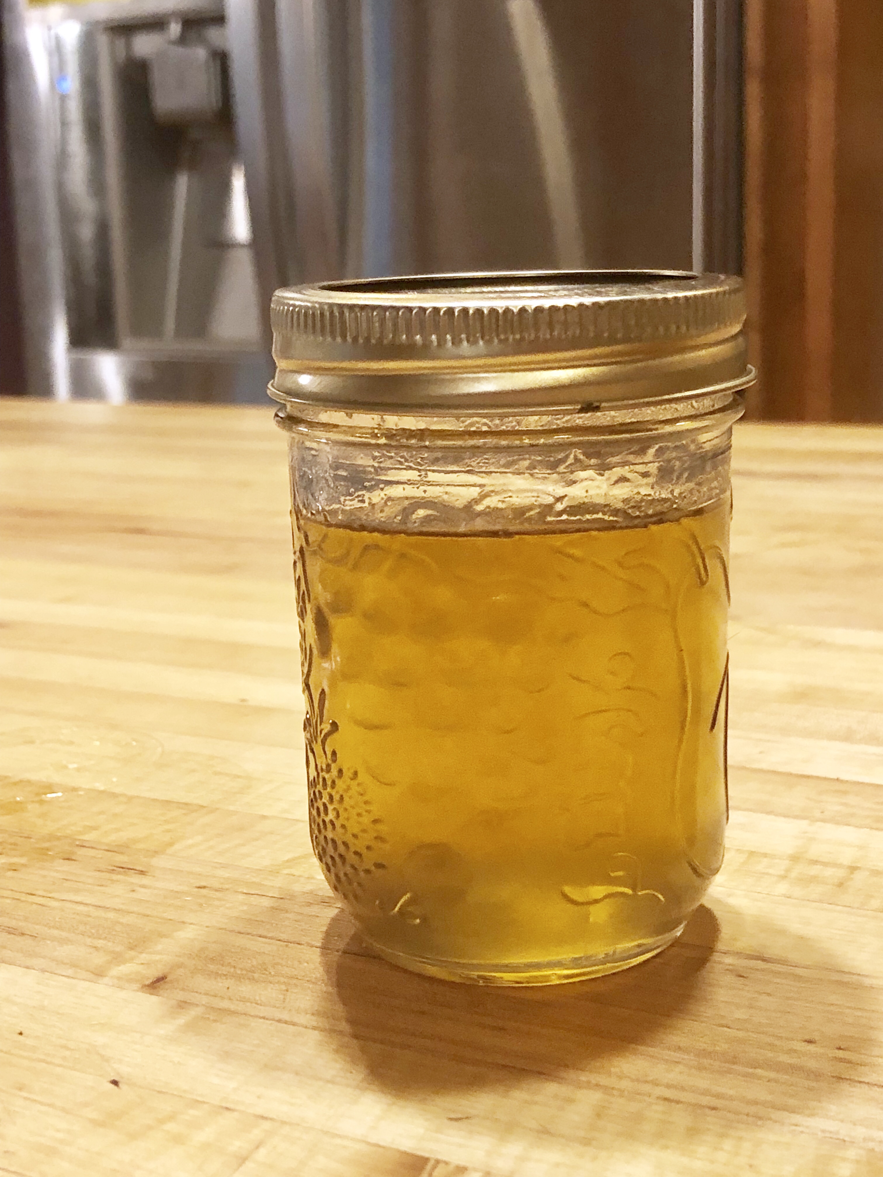 A jar of yellow dandelion jelly in a kitchen 